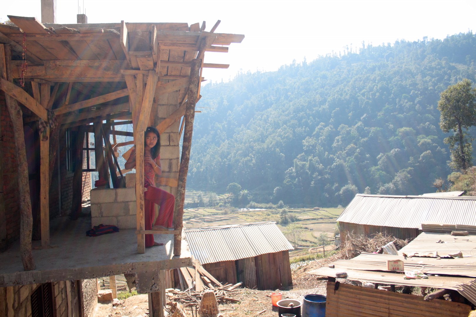 A young girl rests on a beam in her house in Sindhupalchok, Nepal, which is being rebuilt after the 2015 earthquake