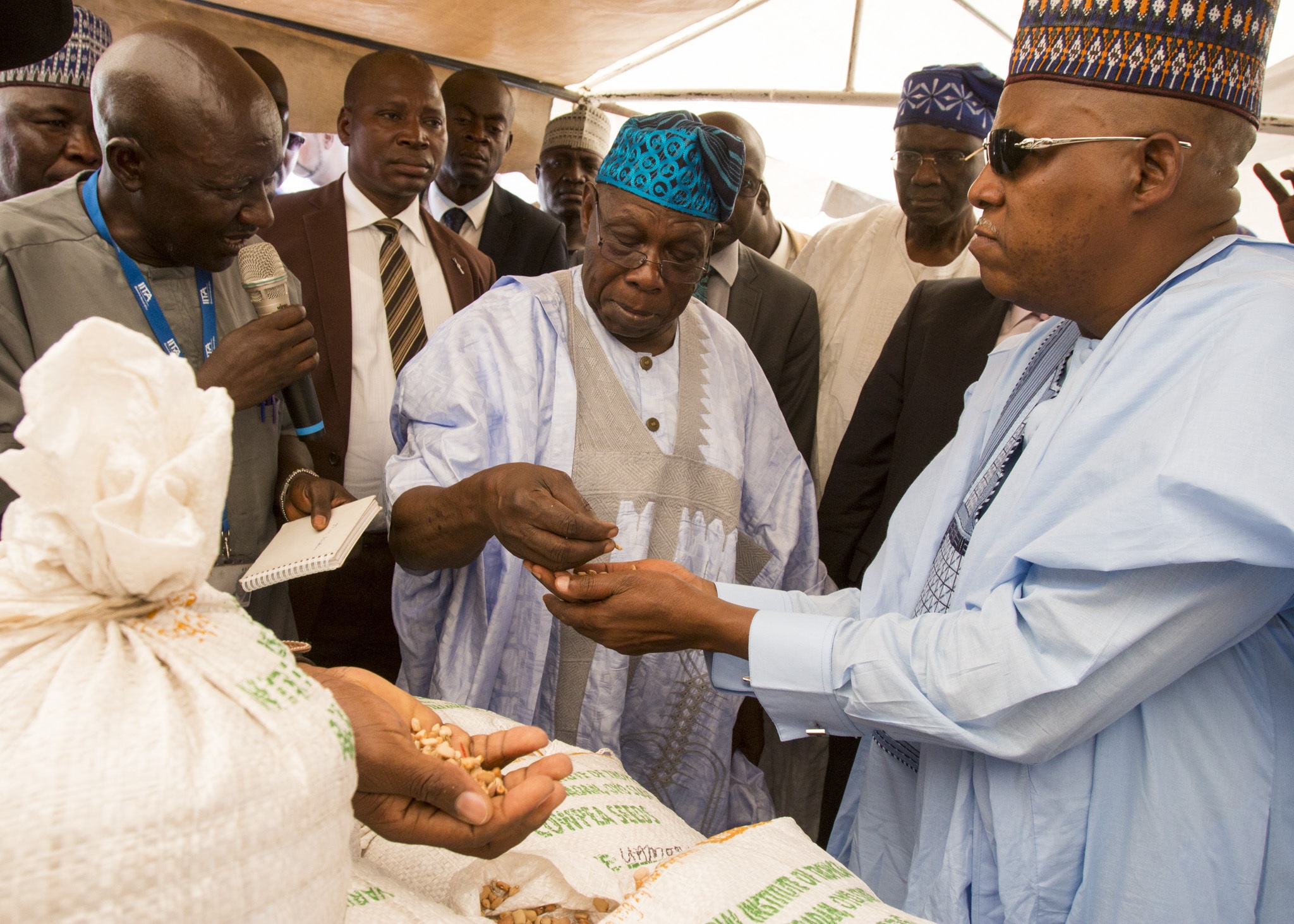 Former president Olusegun Obasanjo, center, and Borno State Governor Kashim Shettima, right, examine seeds