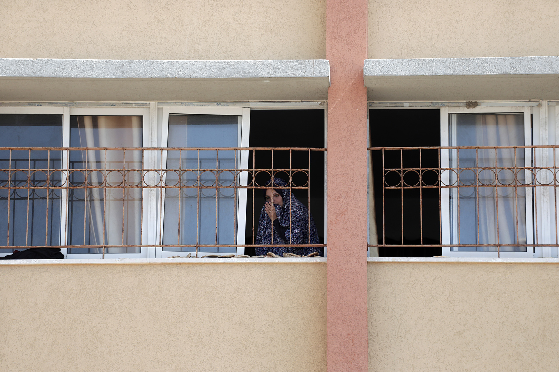 A woman looks out a school window during quarantine