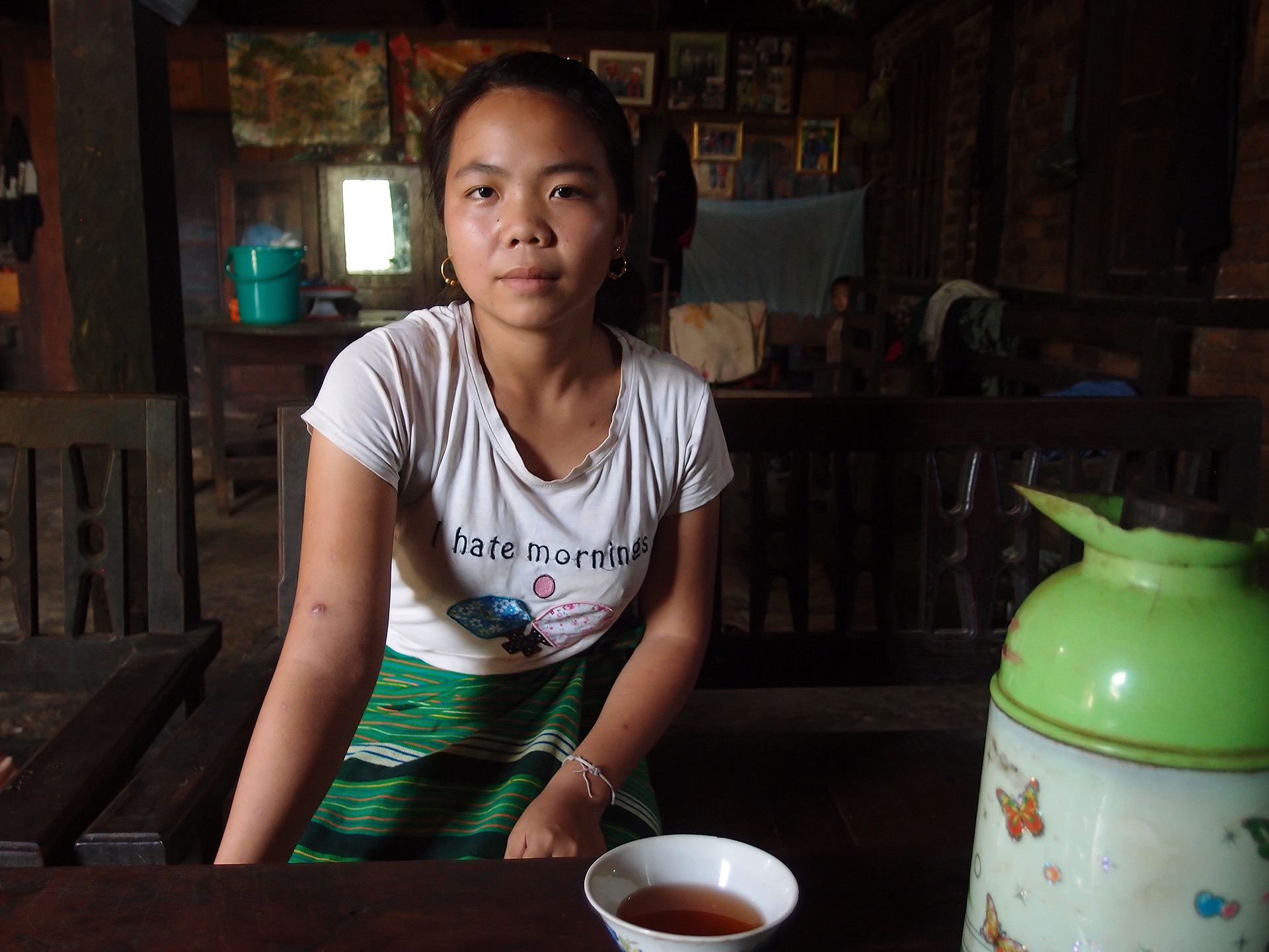 Portrait of young person in Myanmar with tea and a shirt that says "hate mornings."