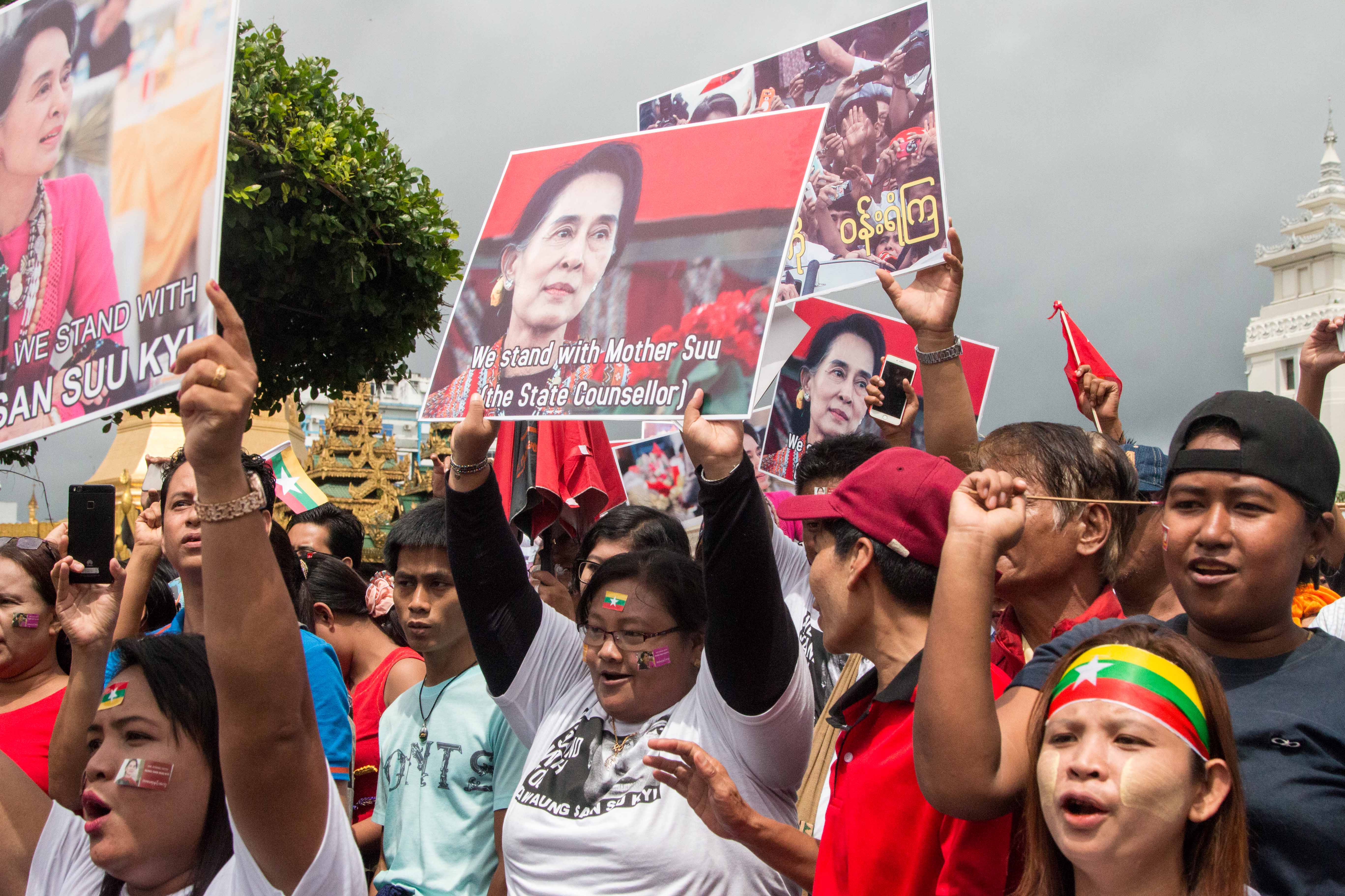 People hold signs supporting Aung San Suu Kyi