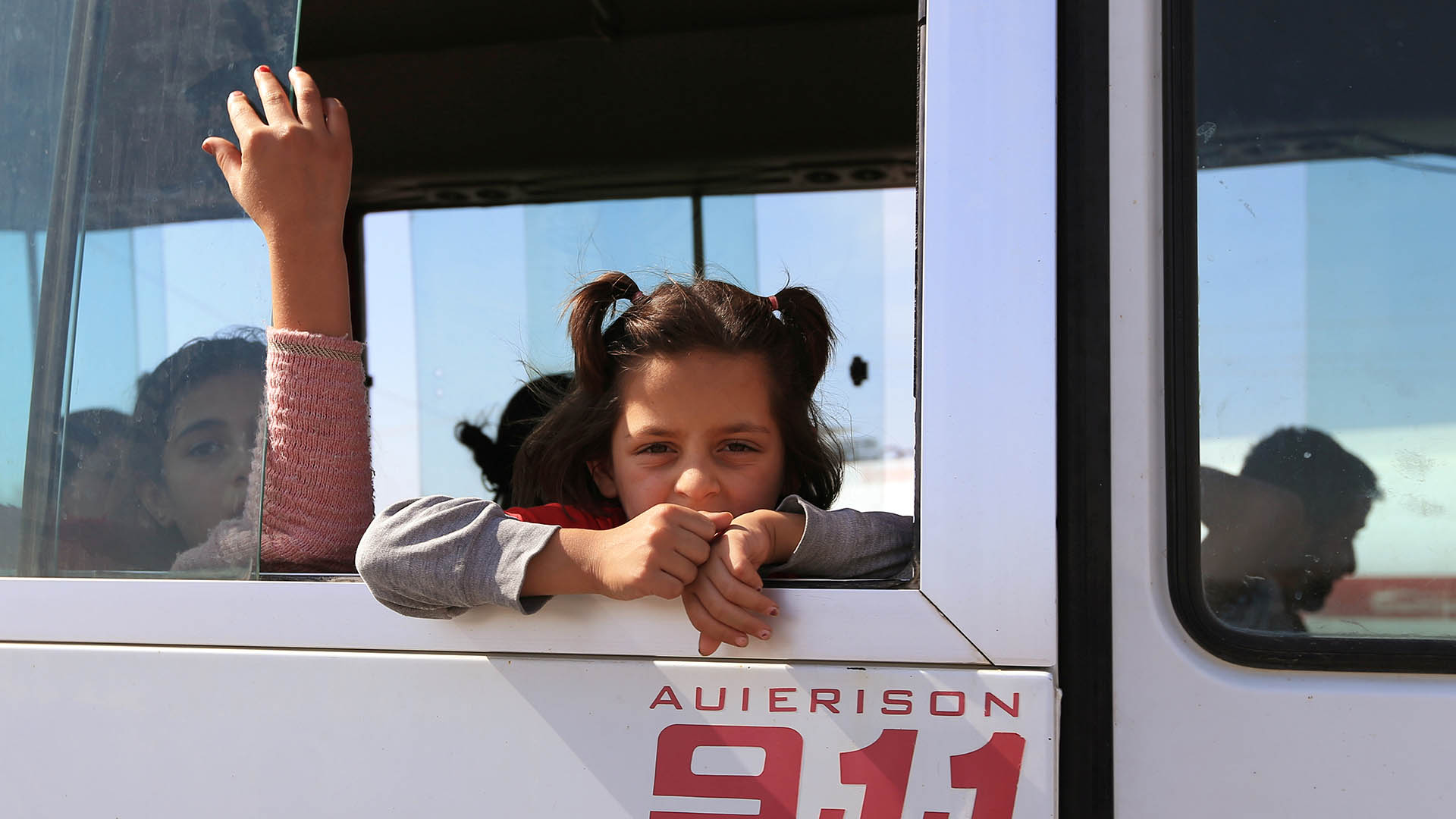 A Syrian child who fled violence with her family after the recent Turkish offensive is taken by bus to a displacement camp near Dohuk in northern Iraq. 