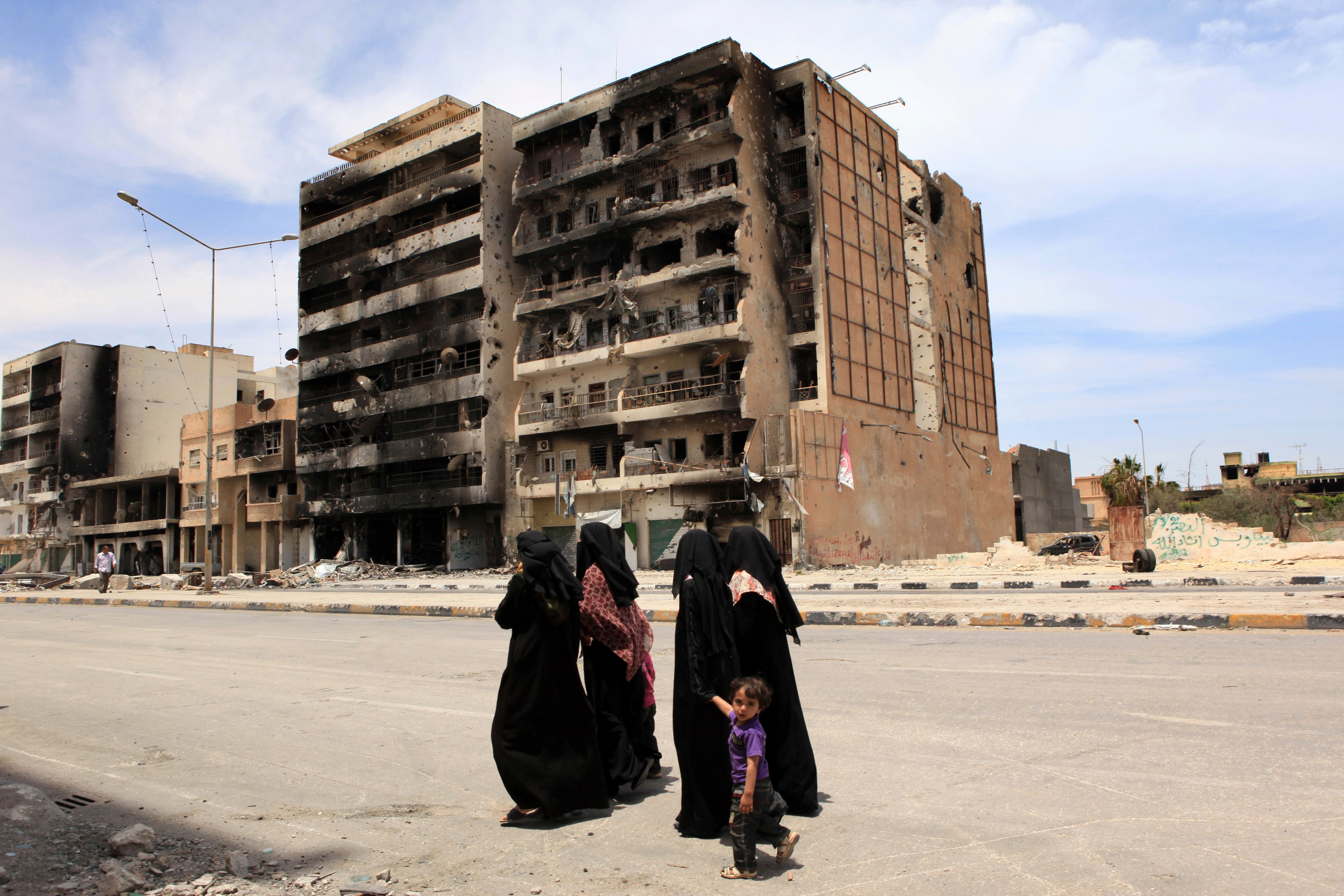 Women walking in front of bombed out buildings in Misrata