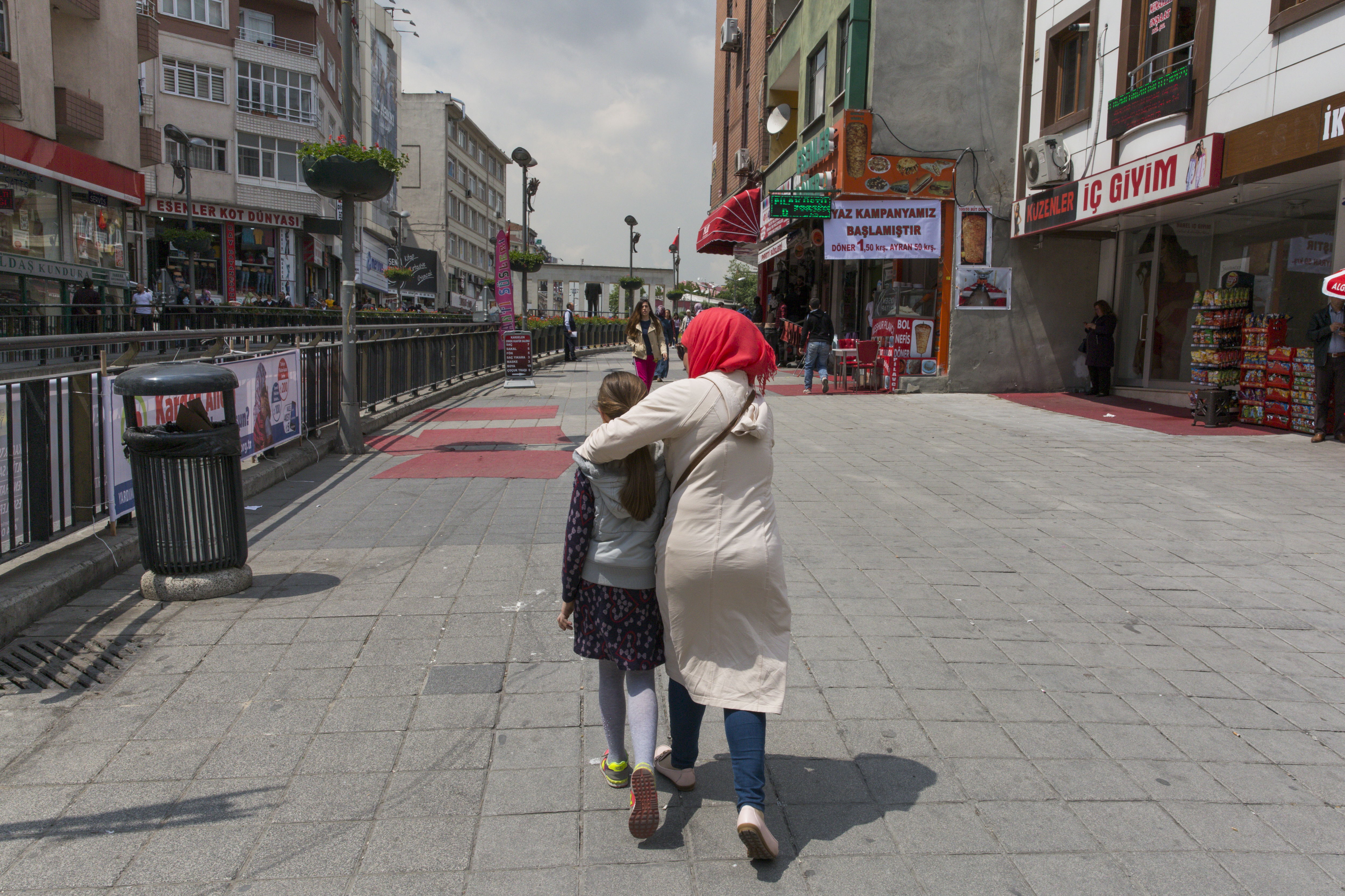 A woman and her daughter walk away from camera on the streets of Istanbul