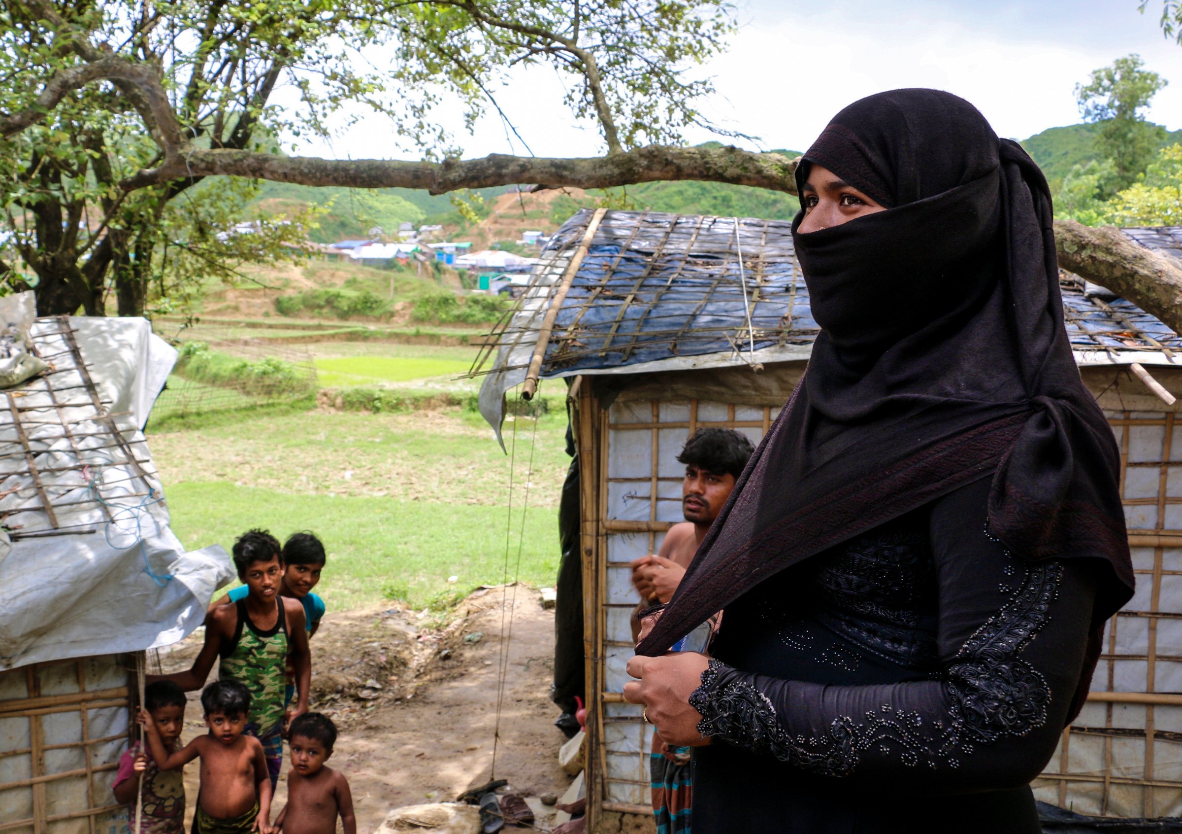 A photo of woman in front of camp buildings smiling with several people behind her