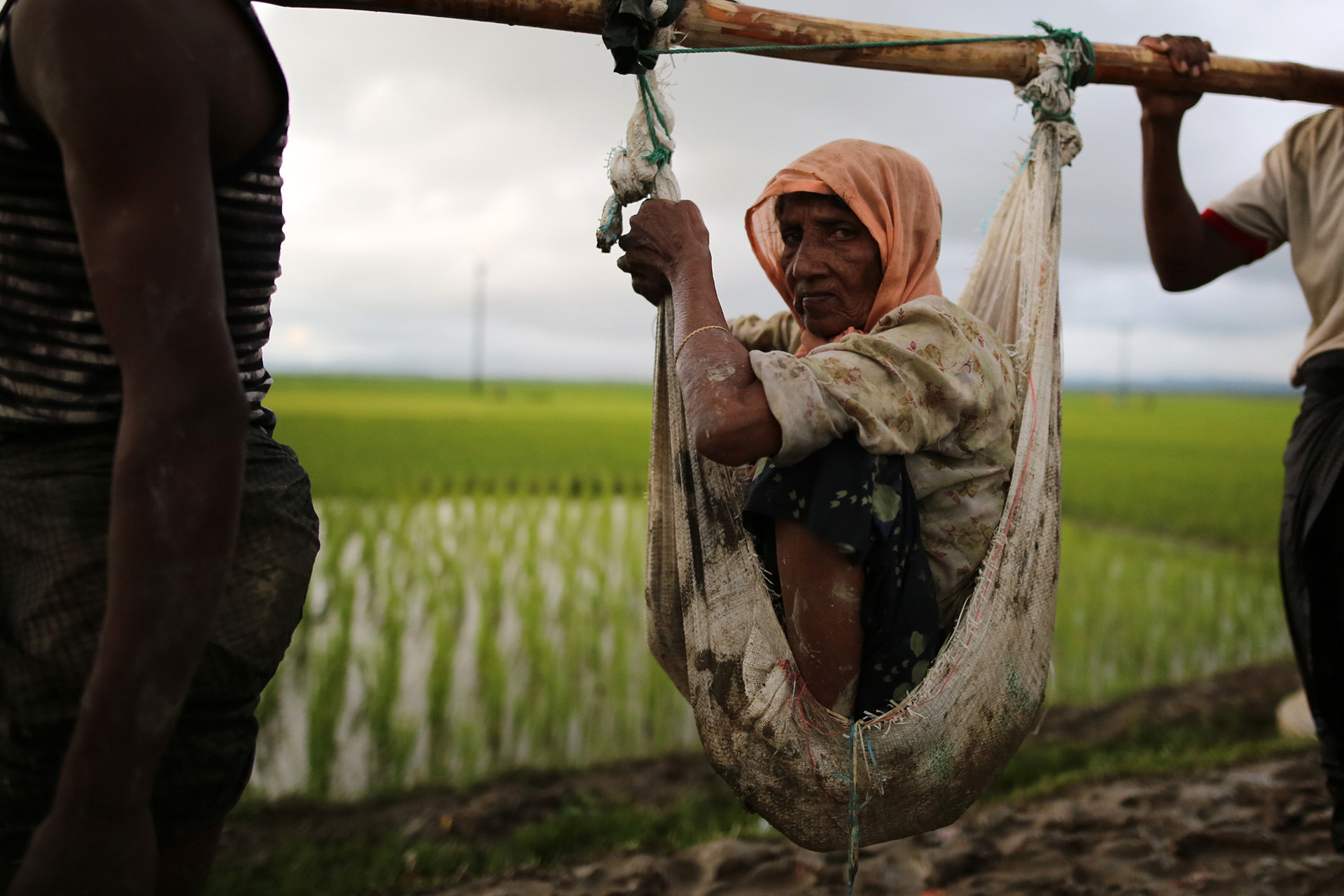 An elderly Rohingya woman is carried on poles