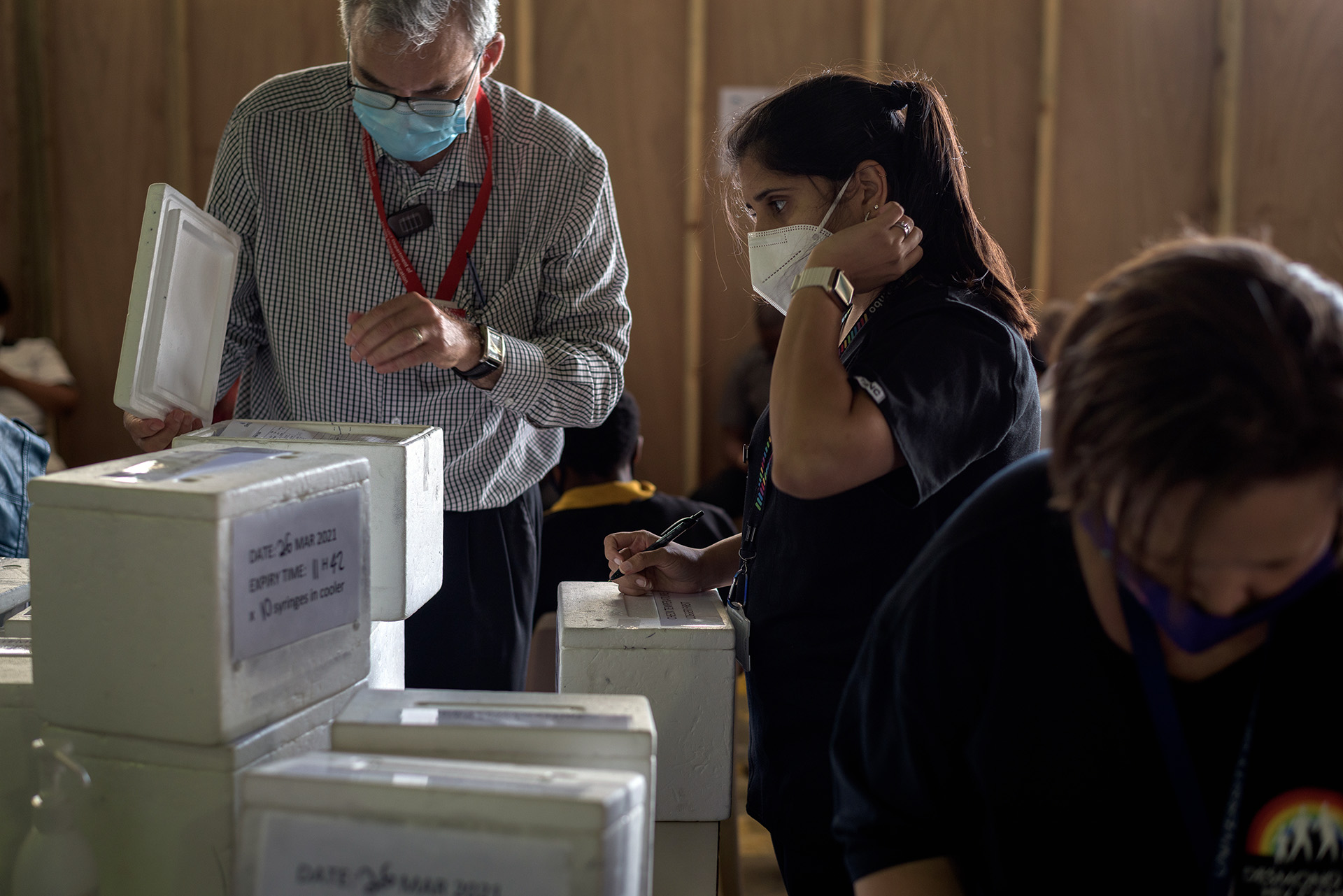 Staff check boxes of vaccines in styrofoam boxes.