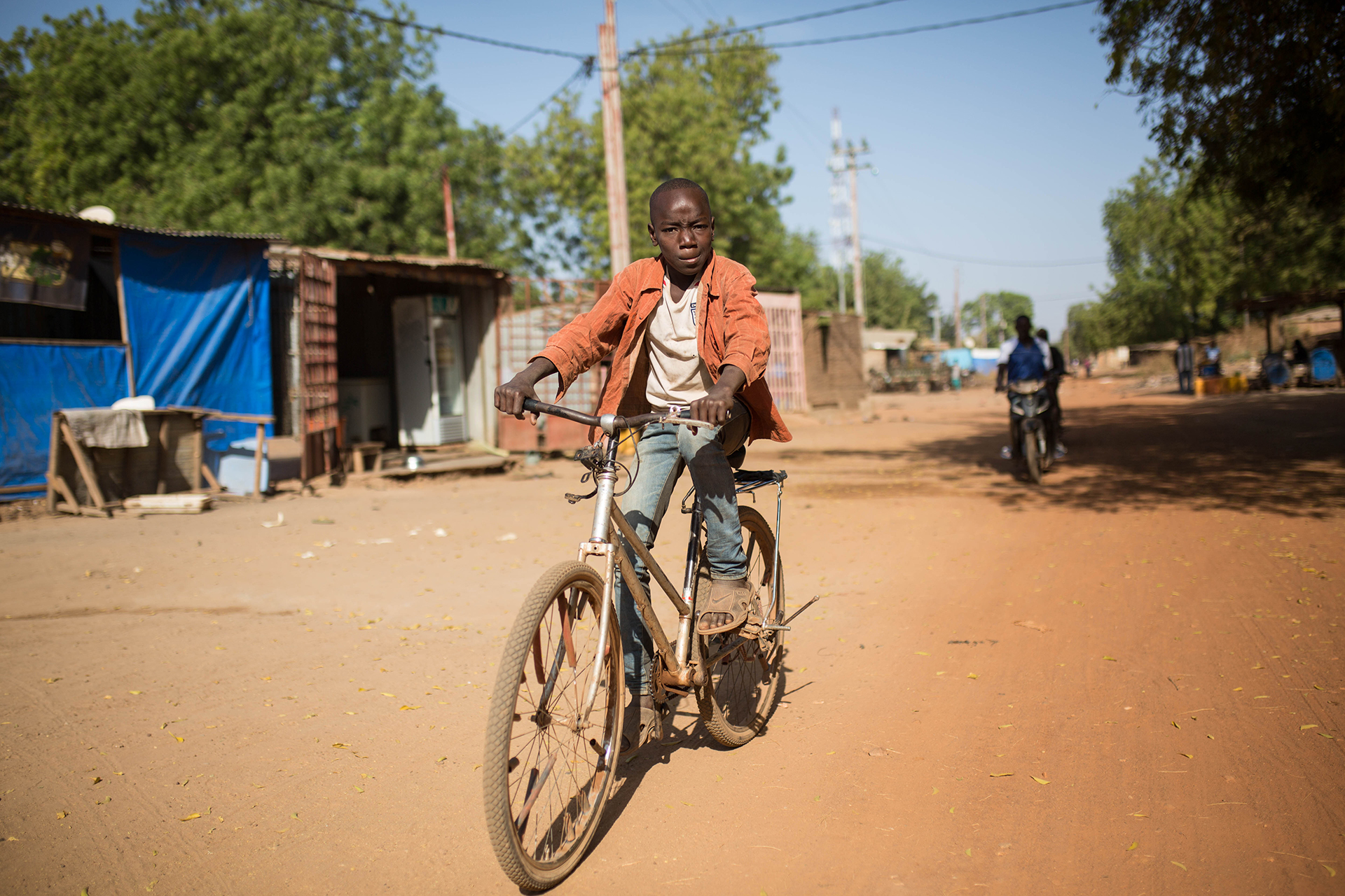 A young boy on a bike makes a serious face at the camera