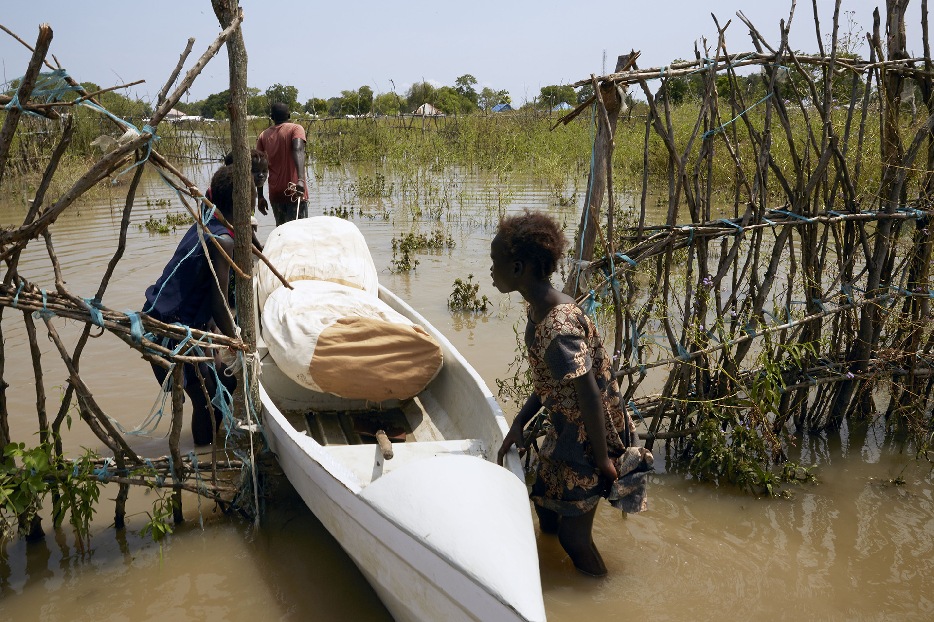 A man and three young girls use a canoe to transport their belongings on what was once a dry footpath leading away from Pibor’s airstrip. The rains are likely to continue until at least the end of November, putting even more people at risk.