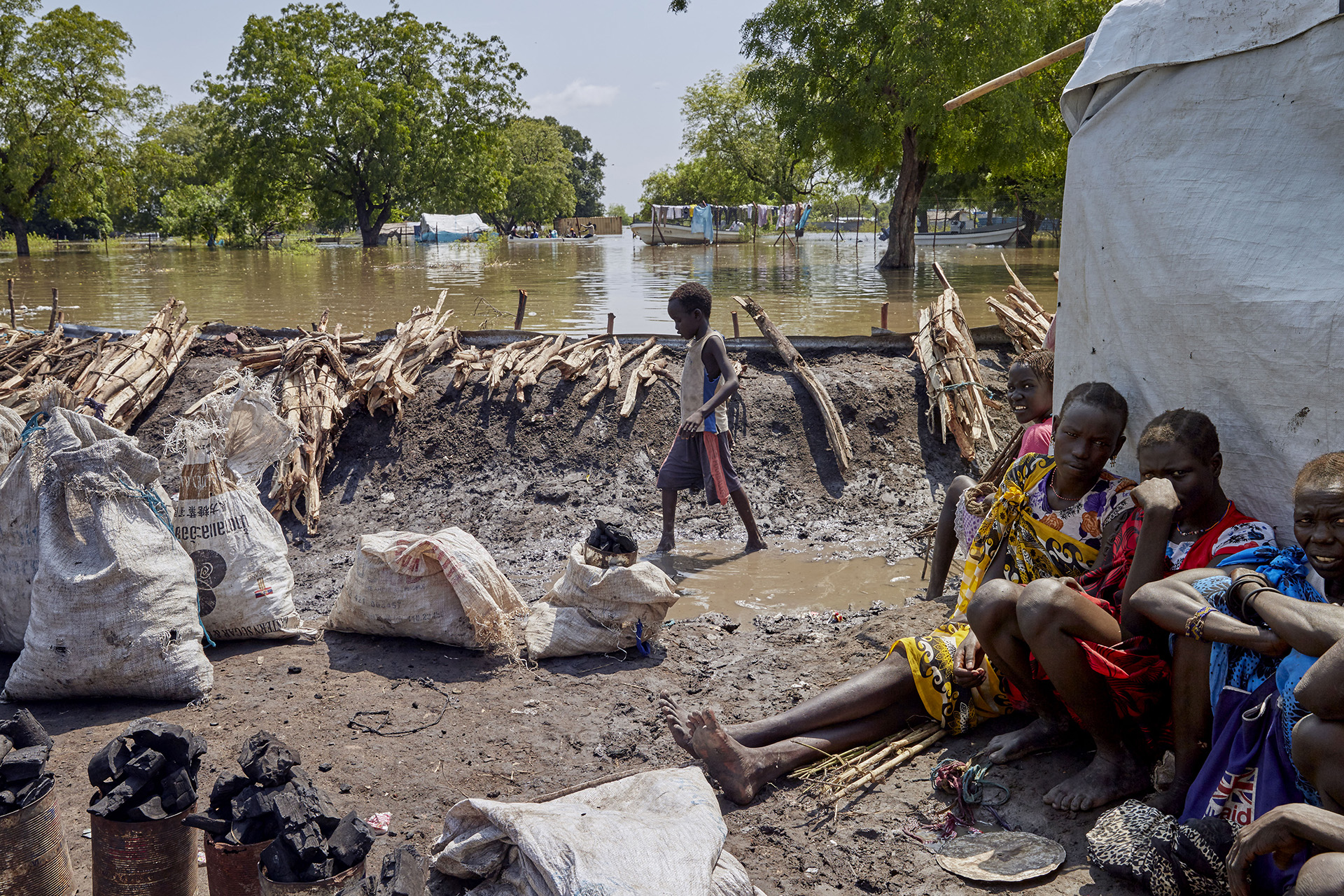 A boy walks beside a man-made mud barrier that is keeping the floodwaters away from a small patch of dry land where roughly 2,700 people are living in makeshift shelters.