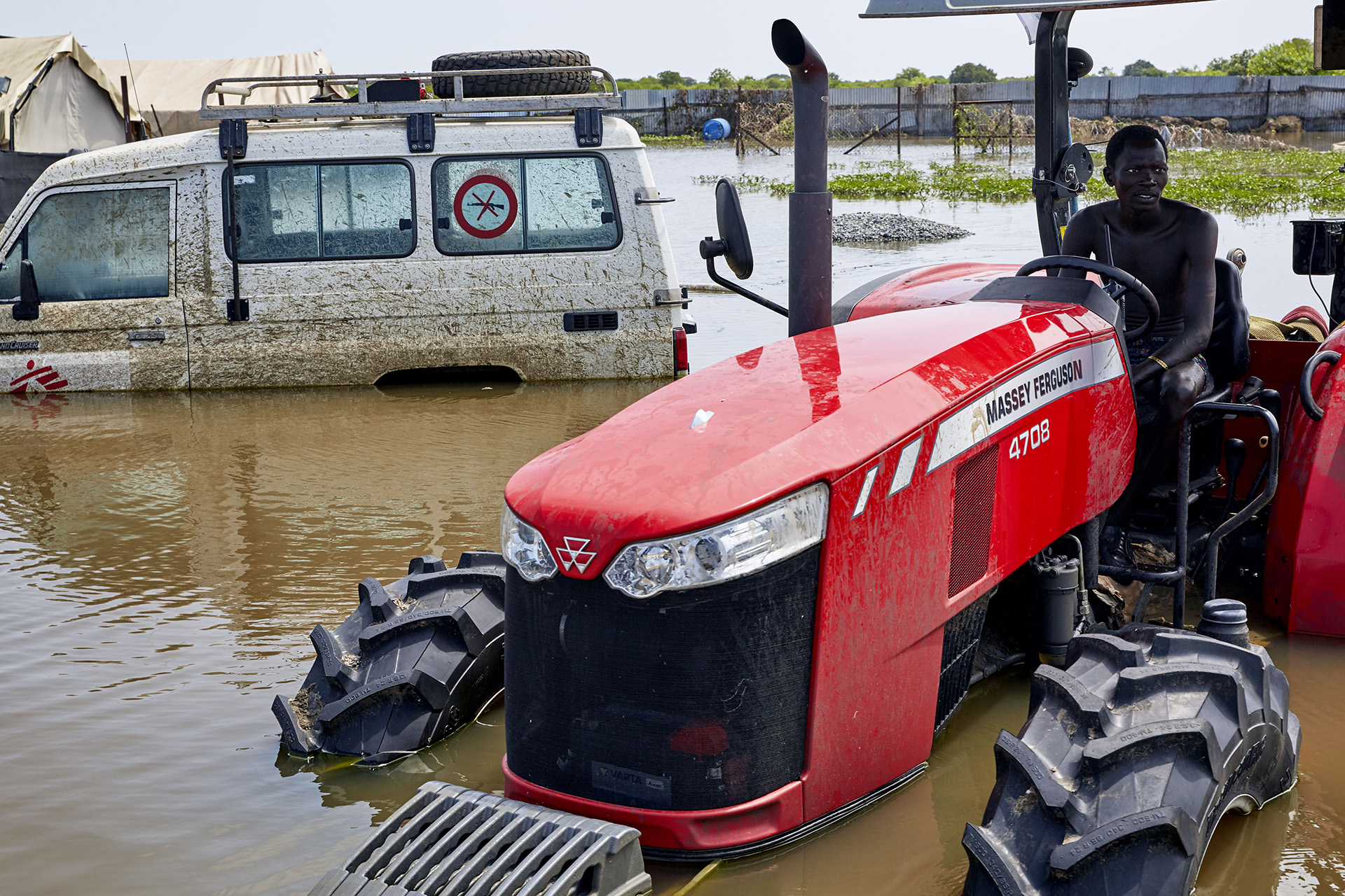 A man sits in a flooded tractor within the compound of a now-defunct MSF primary healthcare centre in central Pibor.