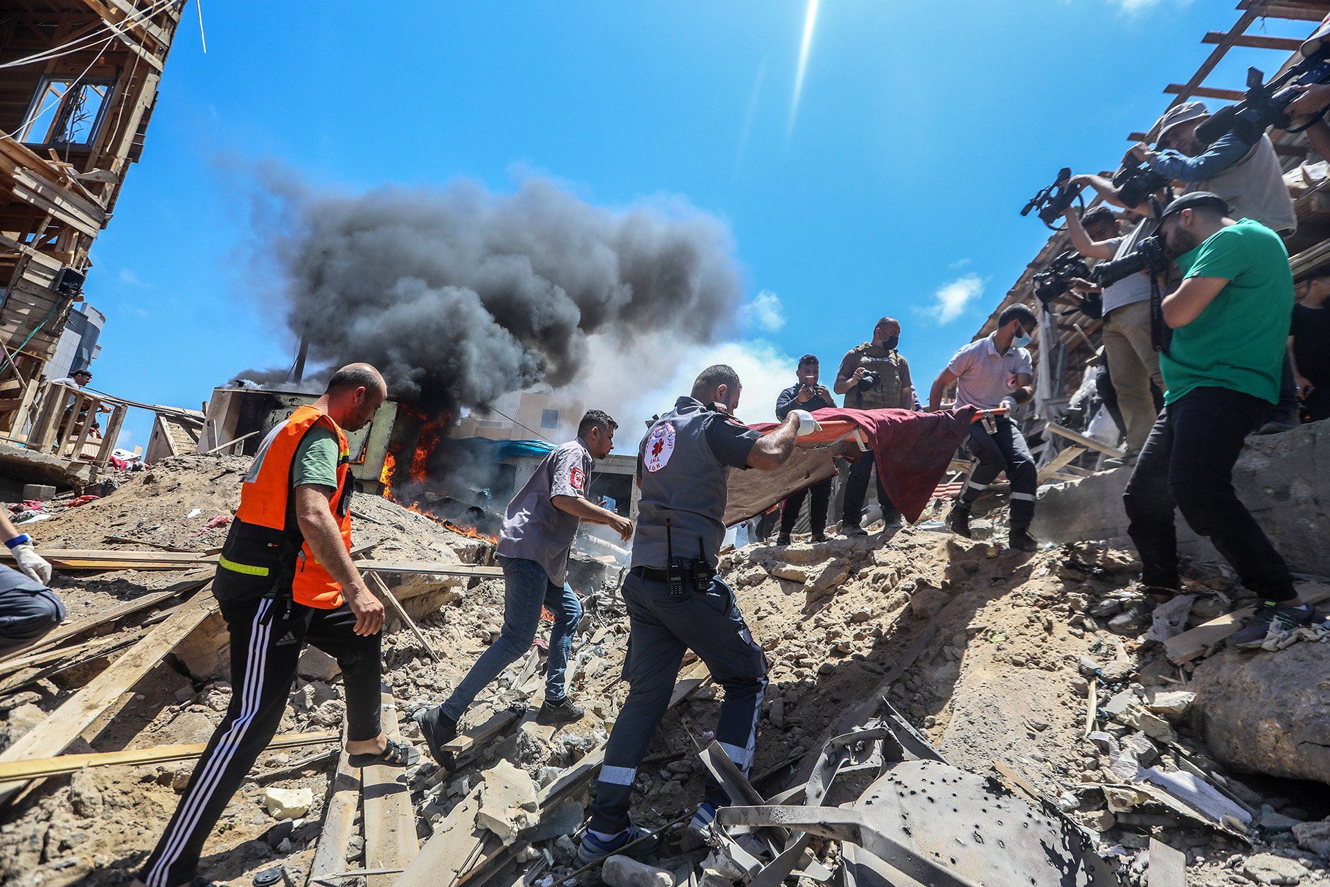 Several medics lift a stretcher from a pile of rubble. 