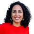 This is a headshot of Khairunissa Dhala. She's pictured smiling and wearing a bright red blouse.