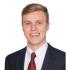 Dalton Price smiles widely. He wears a suit and red tie.