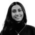 Nilofar Absar is pictured smiling at the camera in this headshot. She wears a dark turtle-neck sweater. 