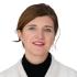 This is a headshot of Jessica Bither. She wears a black turtleneck and white coat. She smiles at the camera.