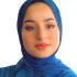 This is a headshot of Nour ElAssy. She is pictured smiling slightly and wearing a teal head scarf.