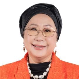 A headshot of Jemilah Mahmood. She is pictured smiling and wearing an orange blazer and black head covering.