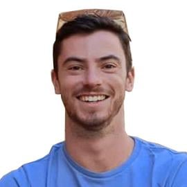 Adam Ettelbrick is pictured smiling at the camera with his arms crossed in front of his chest. He wears a cornflower blue t-shirt.