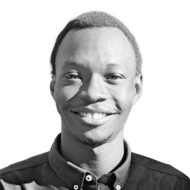 A headshot of Butros Nicola. He is pictured smiling and wears a button up shirt.