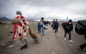 Group of men, women, and children, carrying bags across the border in Chile. 