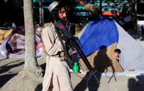 A Taliban fighter walks past the tents of a displaced family in Shahr-e Naw park in the Afghan capital, Kabul, on 14 October 2021.