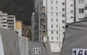 Tent city in West Kahramanmaraş against the backdrop of damaged buildings.