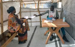 A South Sudanese woman who is a returnee from Sudan holds a child on her lap as she speaks with a medical worker at a transit centre in the town of Malakal. 