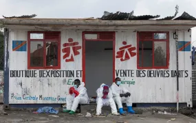 Red Cross volunteers wearing HAZMAT suits sit and wait in front of a container booth for a truck carrying the bodies of victims who died in a jailbreak and fire at a prison in Goma, which was seized by M23 rebels and Rwandan troops in late January.