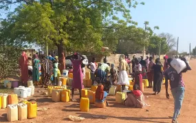Residents of Abyei town gather at a water point and take shade under a tree. The arrival of displaced people from Sudan has strained local infrastructure in the disputed region. 
