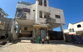 Three of Mohamed al-Astal's children in front of their partially destroyed home in Khan Younis, Gaza.