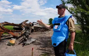 Afrim Bardoniqi, a technical adviser with the Danish Refugee Council, stands in front of a tank destroyed by an anti-vehicle mine as his team demines a road in the Chernihiv region.