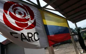 A woman hangs a Colombian flag next to a FARC political party flag