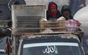 Syrian boys ride on a truck with belongings.