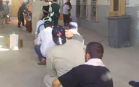 [Iraq] Detainees at Abu Ghraib prison sit on the floor waiting to be "out-processed" before taking a bus home.