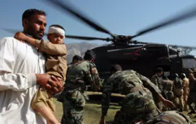 [Pakistan] Muzaffarabad, Pakistan, A father carries his injured son from a German SAR helicopter after they where taken from their devastated village. [Date picture taken: 10/13/2005]