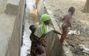 A Congolese woman asylum seeker washes her children with sewer water, outside UNHCR office in Bujumbura, Burundi, 20 August 2007. the Congolese asylum seekers fetch the dirty water for drinking.