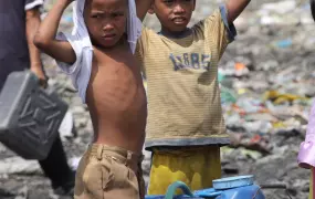 Manila - Children living in a sprawling dumpsite in Manila collect water. A funding crunch due to the global financial crisis means less money used by NGOs and welfare groups for anti-poor projects in the Philippines, officials say