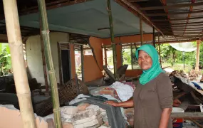 Fatima, 58, stands amidst the ruins of her home in Padang Pariaman district, West Sumatra province. She now sleeps outside the house in a tent with two of her five kids. More than 1,000 people were killed by the 30 September 2009 quake