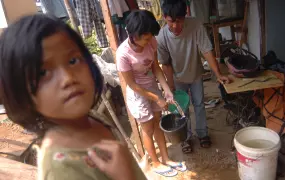 Family members transfer water from one pail to another. Clean water and sanitation are key concern in Jakarta's slums