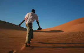 Man walking across a sand dune in Northern Sudan. For generic use