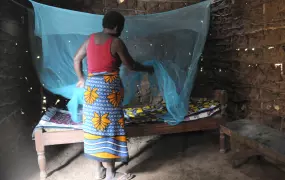 Woman spreading a net over her bed. Malaria. For generic use