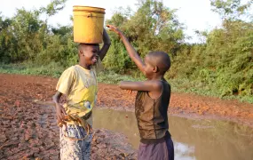 Children play near a dried up water pan in Barchando, Bondo