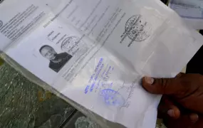 Francis William, a Tanzanian migrant living in Athens, shows his temporary asylum seeker document after his office was smashed up by a racist mob