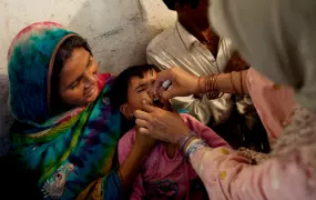 A toddler receives polio drops from a mobile health clinic, at a school-turned relief camp in Tando Adam, Sanghar district, Sindh province, Pakistan