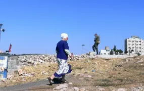 A settler woman walks past an Israeli soldier standing guard in East Jerusalem. As Israeli settlements around the city increase, the International Crisis Group said in a recent report: “for many Arab East Jerusalemites, the battle for their city is all 