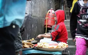 A young Chin refugee cooks traditional Burmese food on a busy street market in Aizawl