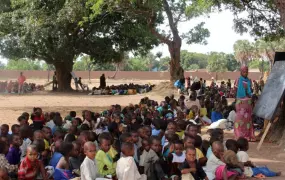 A volunteer teacher holds a class under the trees in Doyaba transit camp in Sarh, southern Chad, May 2014. Some 3,200 primary and pre-primary school age children are enrolled in the school, set up by displaced teachers from CAR.