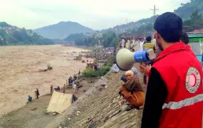 A response team member of the Pakistan Red Crescent Society issues an alert on a mega phone to people near the junction of Jhelum and Neelum rivers in Muzaffarabad district.