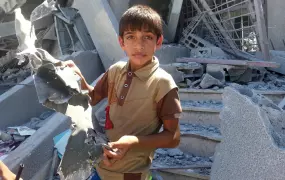 A child holds remnants of an Israeli rocket found in his destroyed school